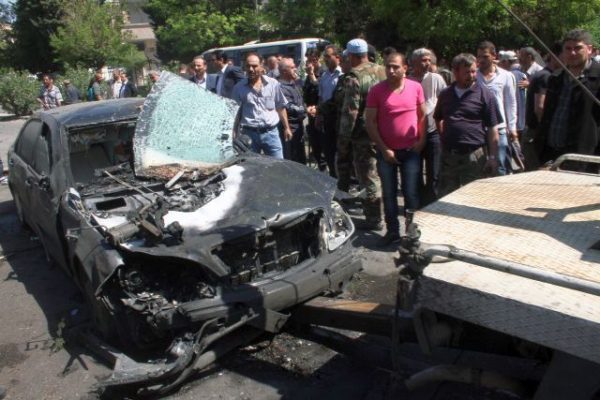 epa03681036 Syrians gather near a damaged vehicle after a bomb explosion, allegedly targeting Syrian Prime Minister Wael al-Halqi, in Damascus, Syria, 29 April 2013. The Syrian premier survived a bomb attack near his convoy in the upscale neighborhood of Mezzeh, Damascus, state television reported. The opposition Syrian Observatory for Human Rights said five civilians were killed in the bombing. EPA/STR