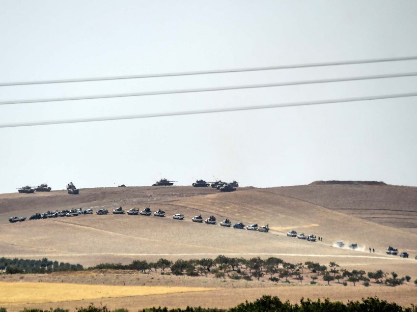 This picture taken from the Turkish Syrian border city of Karkamis in the southern region of Gaziantep, on August 24, 2016 shows Turkish army tanks and pro-Ankara Syrian opposition fighters moving two kilometres west from the Syrian Turkish border town of Jarabulus. Turkey's army backed by international coalition air strikes launched an operation involving fighter jets and elite ground troops to drive Islamic State jihadists out of a key Syrian border town. Turkey's state-run Anadolu news agency reported that pro-Ankara Free Syrian Army (FSA) rebels had already penetrated three kilometres (two miles) inside Syria towards the IS-held town of Jarabulus. The air and ground operation, the most ambitious launched by Turkey in the Syria conflict, is aimed at clearing jihadists from the town of Jarabulus, which lies directly opposite the Turkish town of Karkamis. / AFP PHOTO / BULENT KILIC