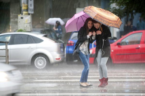 Doua tinere se adapostesc sub umbrele in timp ce asteapta sa traverse Soseaua Mihai Bravu in timpul unei ploi torentiale de vara, in Bucuresti, vineri, 20 iunie 2014. CODRIN PRISECARU / MEDIAFAX FOTO